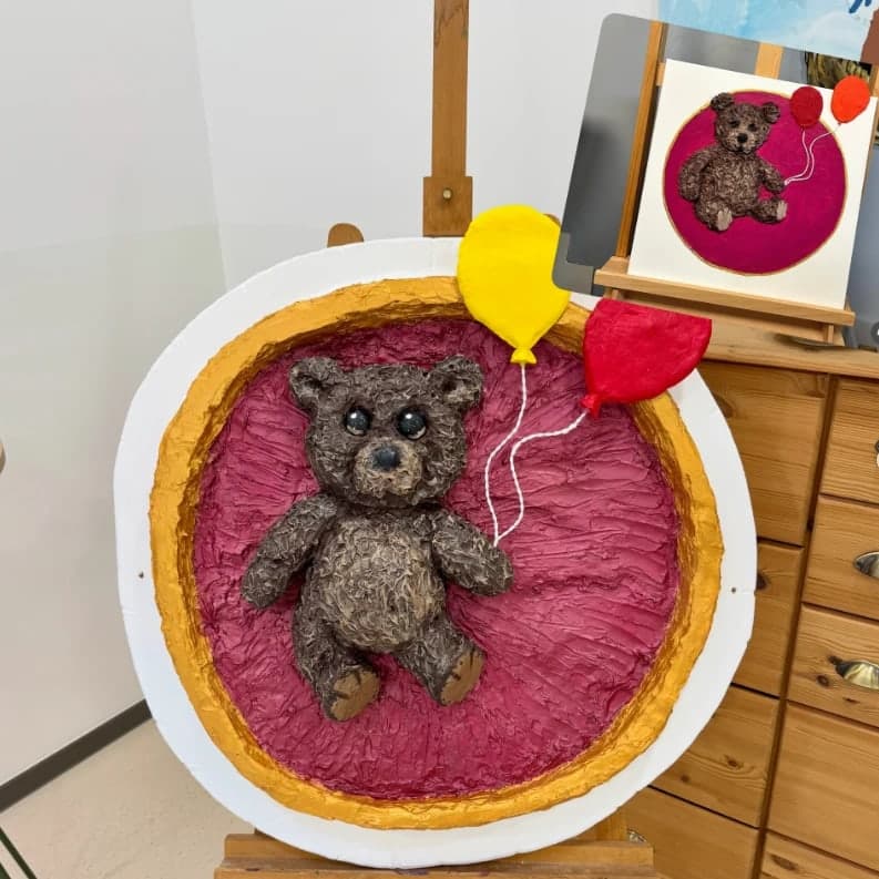 Teddybär mit zwei Luftballons: im Hintergrund das gemalte Bild, im Vordergrund das daraus modellierte Relief
